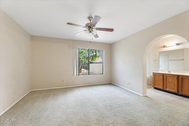 interior space with arched walkways, ceiling fan, baseboards, and light carpet
