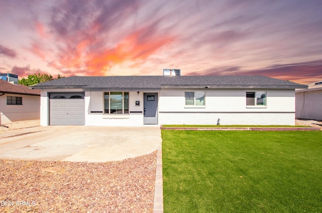 ranch-style home with a garage and a lawn