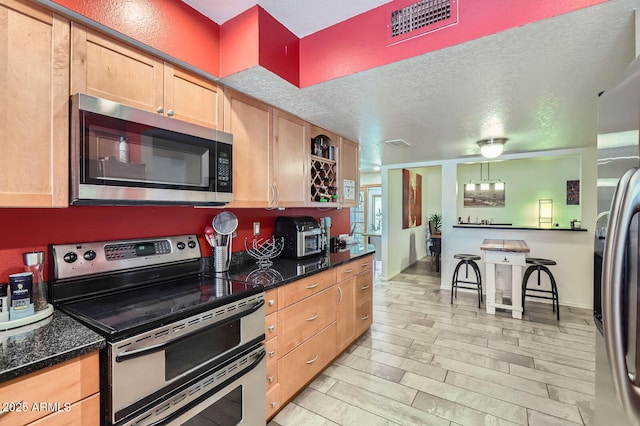 3924 E Cortez St, Phoenix, AZ 85028 - kitchen featuring stainless steel appliances, light brown cabinetry, a textured ceiling, light wood finished floors, and dark stone countertops