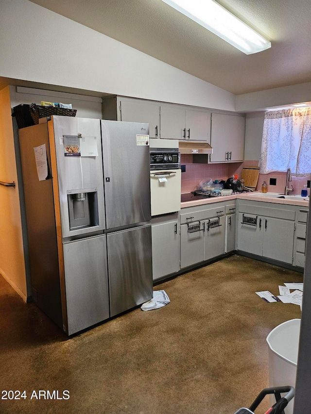 kitchen featuring black gas stovetop, backsplash, vaulted ceiling, white oven, and stainless steel fridge with ice dispenser