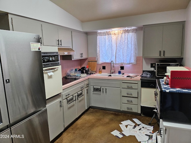 kitchen featuring lofted ceiling, sink, stainless steel fridge, oven, and gas stovetop