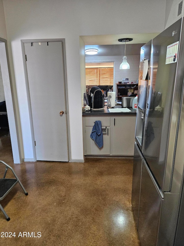 kitchen with stainless steel refrigerator with ice dispenser, pendant lighting, and white cabinets