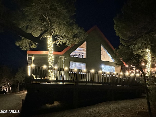 back house at twilight with a wooden deck