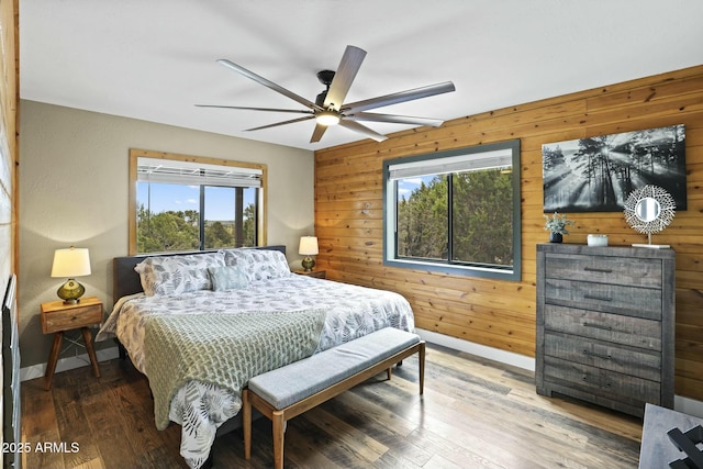 bedroom featuring ceiling fan, hardwood / wood-style floors, and wood walls