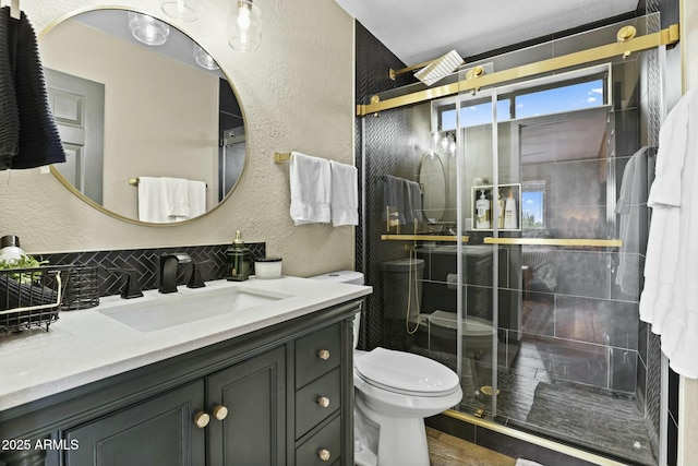 bathroom featuring a shower with shower door, vanity, and toilet