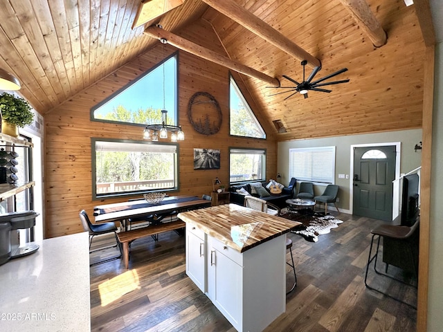 kitchen featuring wooden walls, a kitchen island, beamed ceiling, white cabinets, and wooden ceiling