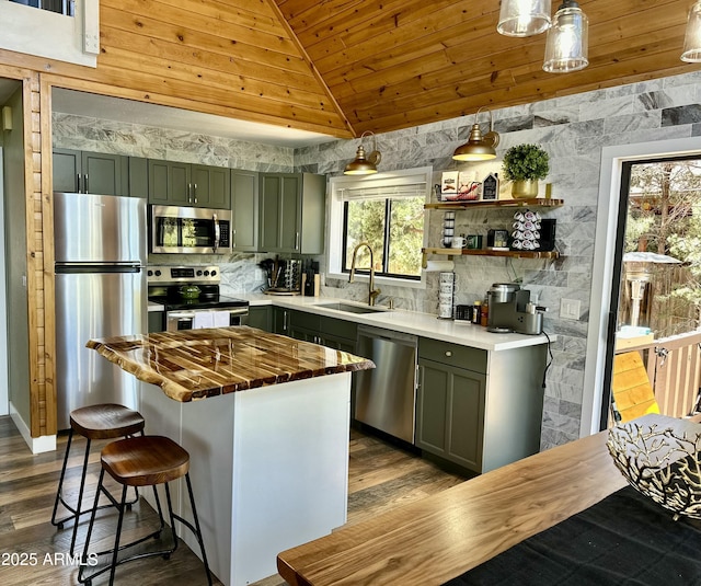 kitchen with vaulted ceiling, appliances with stainless steel finishes, hanging light fixtures, green cabinetry, and sink