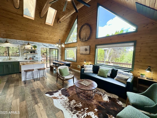 living room featuring high vaulted ceiling, a skylight, beamed ceiling, and wooden walls