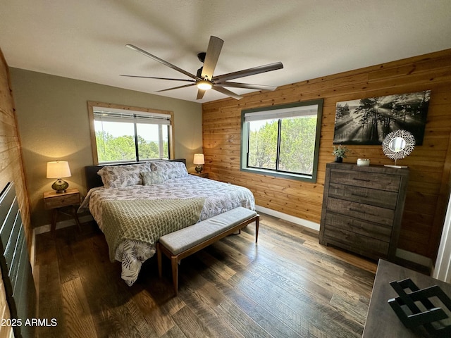 bedroom featuring dark hardwood / wood-style flooring, wood walls, and ceiling fan