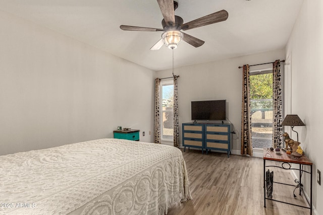 bedroom with multiple windows, wood-type flooring, and ceiling fan