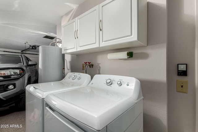 washroom with cabinets, washing machine and dryer, and gas water heater