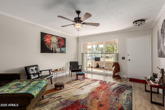 sitting room featuring ceiling fan, crown molding, light hardwood / wood-style flooring, and a textured ceiling