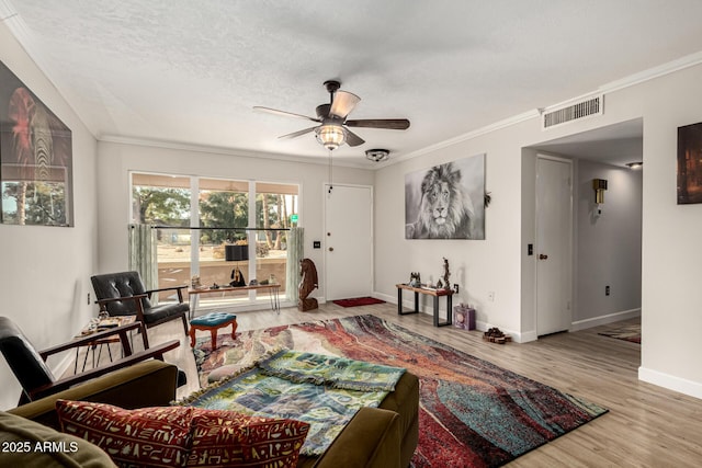 living room with ceiling fan, hardwood / wood-style flooring, ornamental molding, and a textured ceiling