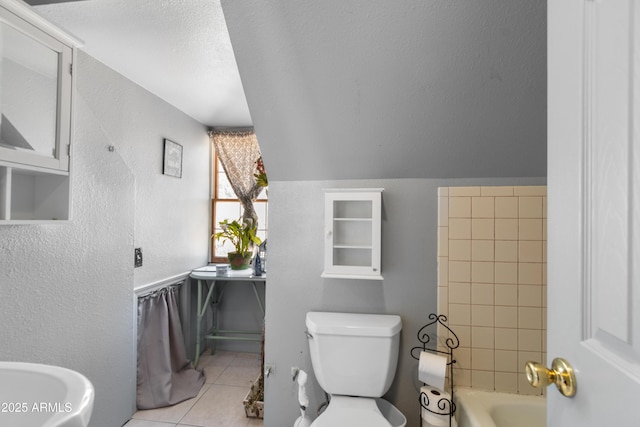 full bath with a bath, tile patterned flooring, a textured ceiling, toilet, and a textured wall