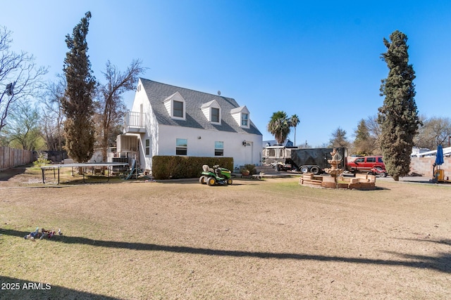 exterior space featuring a shingled roof, a front yard, and fence