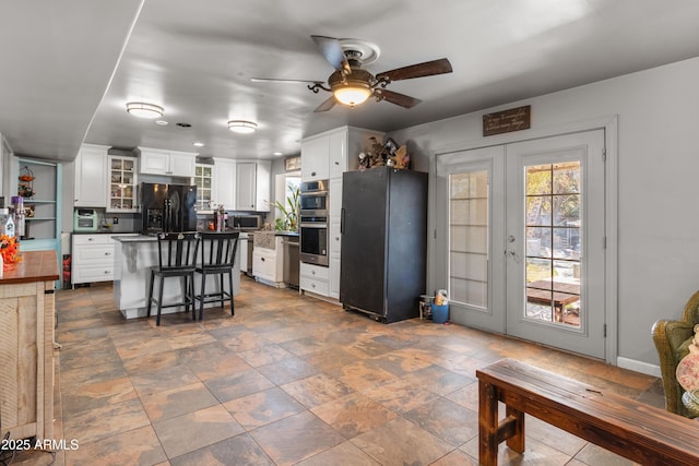 kitchen with black fridge with ice dispenser, white cabinets, a breakfast bar, and freestanding refrigerator