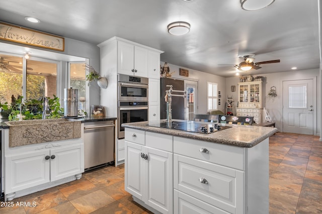 kitchen featuring a sink, appliances with stainless steel finishes, a ceiling fan, and white cabinetry