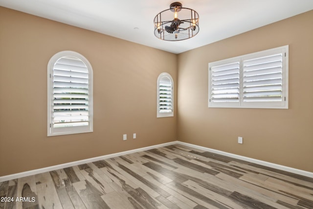 unfurnished room with light hardwood / wood-style floors and a chandelier