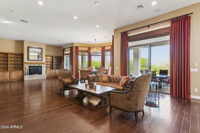 living room featuring an inviting chandelier, dark wood-type flooring, and a stone fireplace