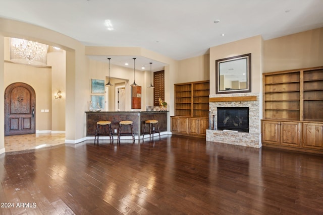 living room featuring a fireplace, dark hardwood / wood-style floors, a chandelier, and built in shelves