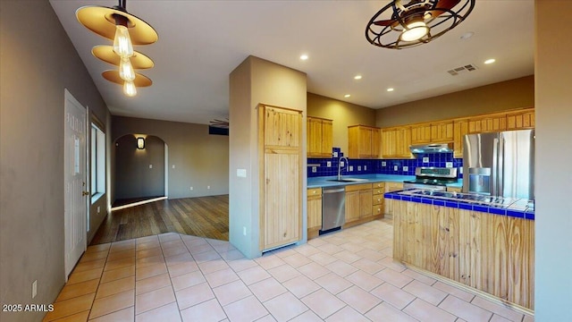 kitchen with tile countertops, ceiling fan, tasteful backsplash, light brown cabinetry, and appliances with stainless steel finishes