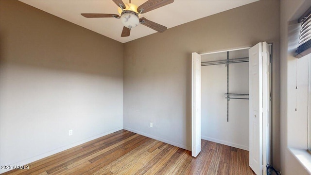 unfurnished bedroom with wood-type flooring, ceiling fan, and a closet