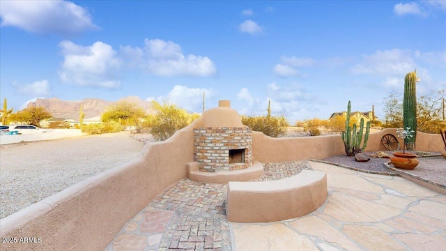 view of patio with an outdoor brick fireplace and a mountain view