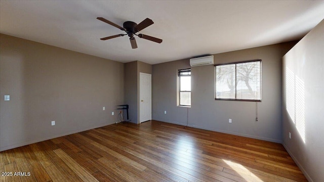 empty room with an AC wall unit, ceiling fan, and hardwood / wood-style flooring