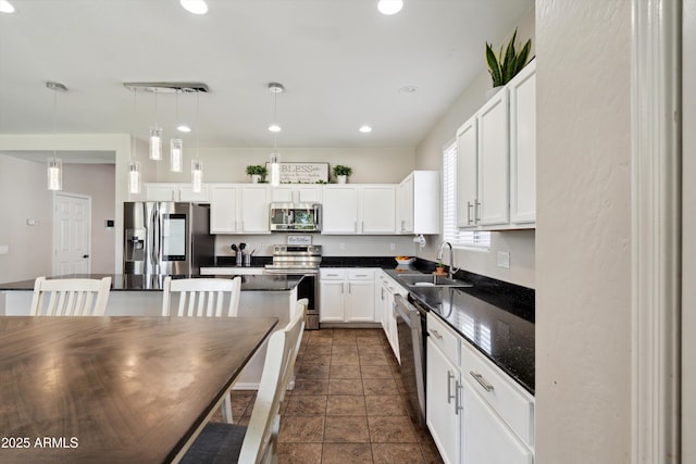 kitchen with a kitchen island, white cabinets, dark countertops, stainless steel appliances, and a sink