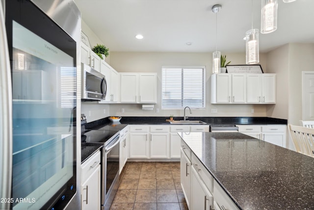 kitchen with stainless steel appliances, decorative light fixtures, white cabinets, and a sink