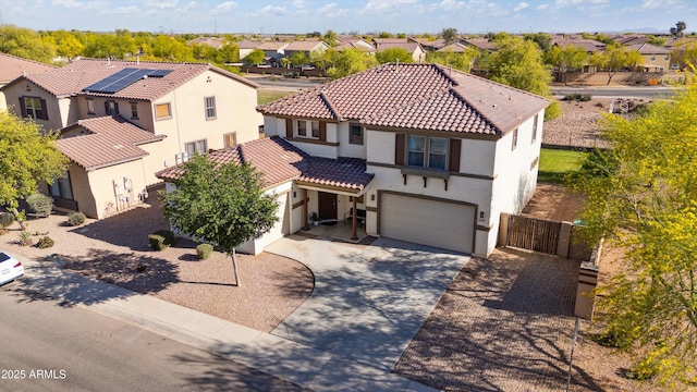 mediterranean / spanish home with a garage, stucco siding, a tile roof, concrete driveway, and a residential view