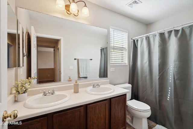 full bath with a sink, visible vents, toilet, and double vanity