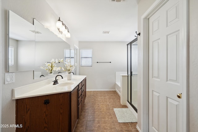 full bath with tile patterned floors, plenty of natural light, vanity, and a stall shower