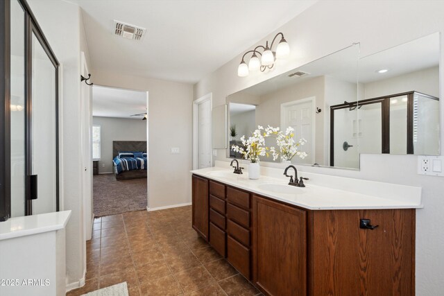 ensuite bathroom featuring a sink, visible vents, a shower stall, and double vanity
