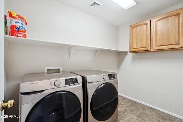 washroom with visible vents, baseboards, cabinet space, and washer and clothes dryer