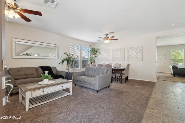 tiled living room with visible vents, ceiling fan, carpet flooring, and baseboards