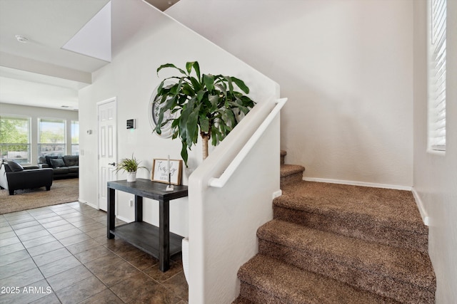 stairway featuring tile patterned flooring, baseboards, and carpet