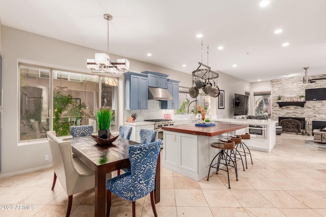 kitchen with pendant lighting, butcher block countertops, tasteful backsplash, high end stainless steel range, and a kitchen bar