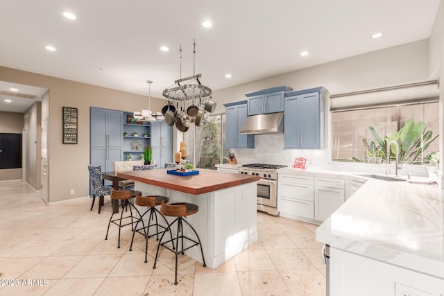 kitchen with sink, high end range, decorative light fixtures, a kitchen breakfast bar, and a kitchen island