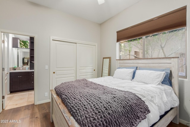 bedroom featuring a closet, wood-type flooring, ensuite bath, and multiple windows