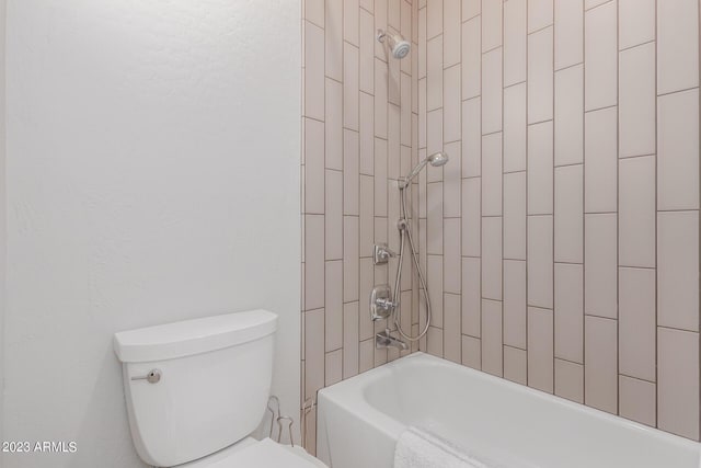 bathroom with tiled shower / bath combo and toilet