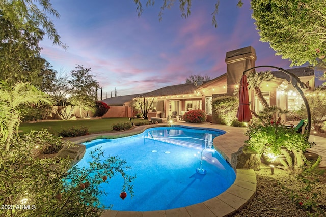 pool at dusk featuring a patio