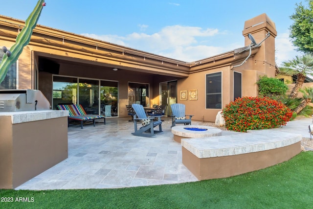 back of house featuring an outdoor kitchen, a patio area, and a fire pit