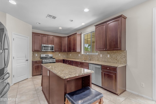 27053 N 172nd Ln, Surprise, AZ 85387 - kitchen featuring appliances with stainless steel finishes, a kitchen island, light tile patterned floors, tasteful backsplash, and light stone counters