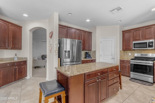 27053 N 172nd Ln, Surprise, AZ 85387 - kitchen with appliances with stainless steel finishes, arched walkways, light tile patterned floors, light stone countertops, and backsplash