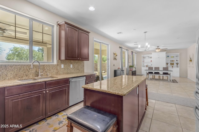 27053 N 172nd Ln, Surprise, AZ 85387 - kitchen with stainless steel dishwasher, a center island, light stone counters, light tile patterned floors, and backsplash