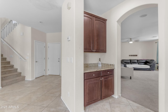 27053 N 172nd Ln, Surprise, AZ 85387 - kitchen featuring arched walkways, light tile patterned floors, ceiling fan, and light stone counters