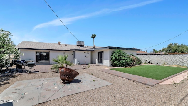 rear view of property featuring a patio, central AC, fence, and a yard