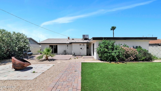 rear view of house with a lawn, central AC unit, a patio area, and fence