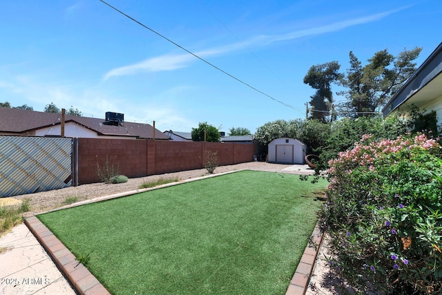 view of yard with a fenced backyard, a shed, and an outbuilding